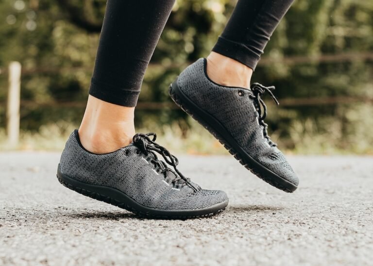 A close up of a pair of feet and lower legs running on concrete wearing Freet Pace barefoot running shoes with a wide toe box