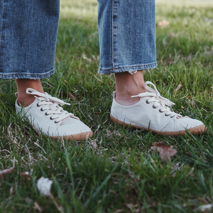 A person walking on shaded grass wearing Mukishoes Sand soft canvas barefoot sneakers with a very flexible outsole