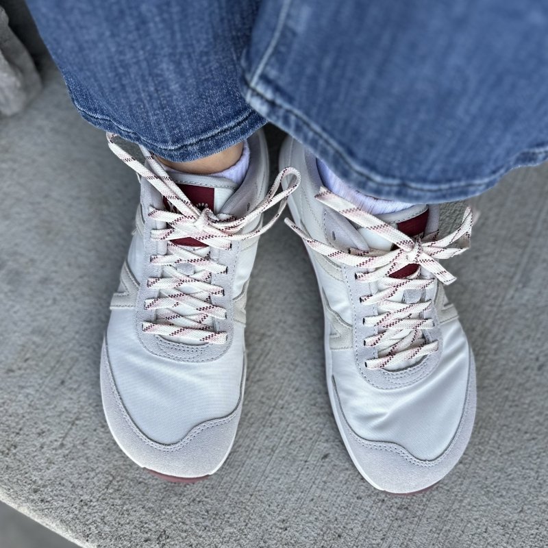 A person's feet in Xero Shoes Wynn sneaker with fun patterned laces and a wide anatomical toe box. Their feet are spread apart slightly.